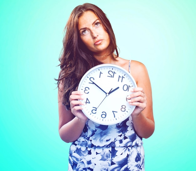 jolie femme en colère tenant une horloge