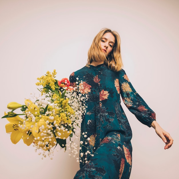 Jolie femme confiante en robe avec bouquet de fleurs fraîches