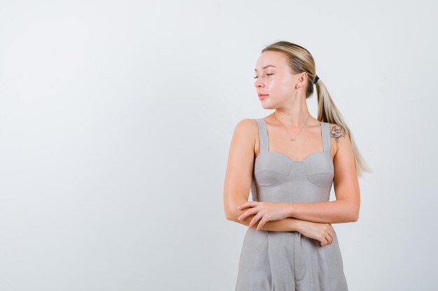 Jolie femme croise les mains ci-dessous en costume gris coupe-bas avec tatouage et à la passionnée