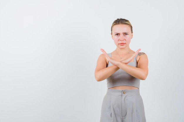 Photo gratuite jolie femme a croisé les mains comme interdite en costume gris coupe-bas avec tatouage et l'air très en colère