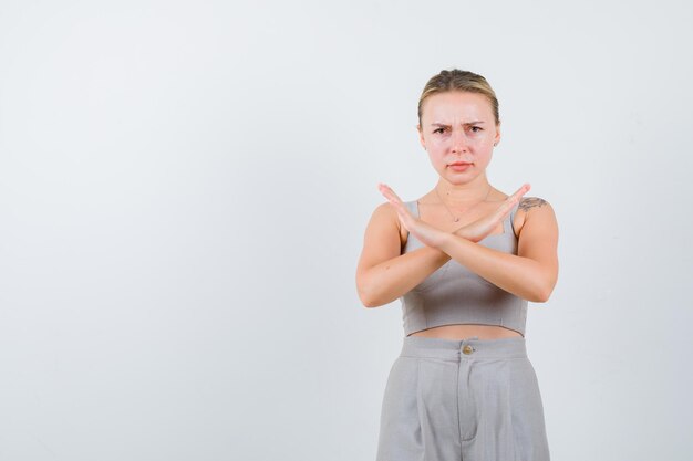 Jolie femme a croisé les mains comme interdite en costume gris coupe-bas avec tatouage et l'air très en colère