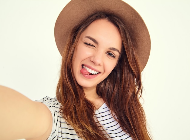 jolie femme dans des vêtements d'été hipster prendre selfie des mains avec téléphone, montrant sa langue