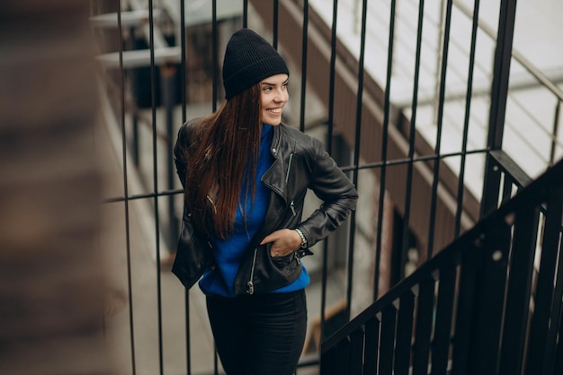 Jolie femme debout dans la rue portant une veste noire