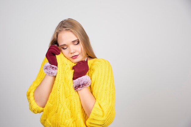 Jolie femme debout et posant dans des gants rouges.