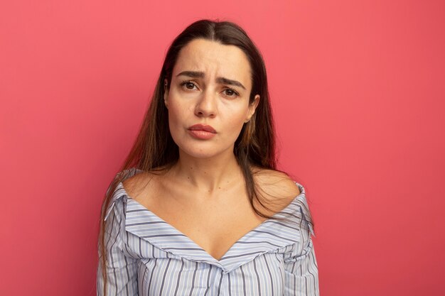 Jolie femme déçue regarde à l'avant isolé sur un mur rose