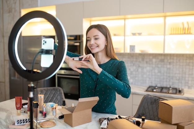 Jolie femme démontrant de nouveaux cosmétiques et semblant impliquée