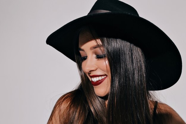 Jolie femme élégante aux yeux charbonneux et aux lèvres noires souriant et s'amusant, dansant, profitant de la fête, la main. Fille maigre à la mode posant sur un mur isolé