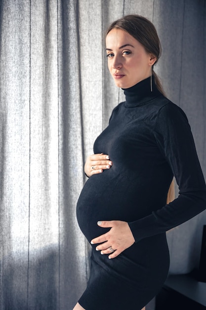 Photo gratuite jolie femme enceinte à l'intérieur de la pièce près de la fenêtre