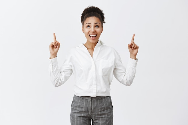 Jolie femme entrepreneur afro-américaine pointant les doigts vers le haut et souriant