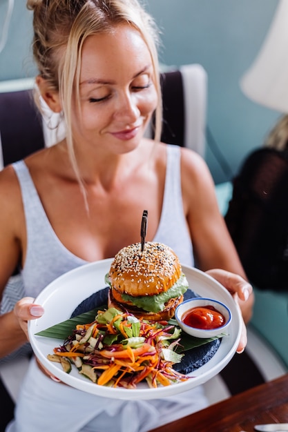 Jolie femme européenne affamée de hamburger juteux au café d'été