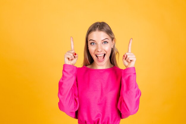 Jolie femme européenne en chemisier rose sur mur jaune