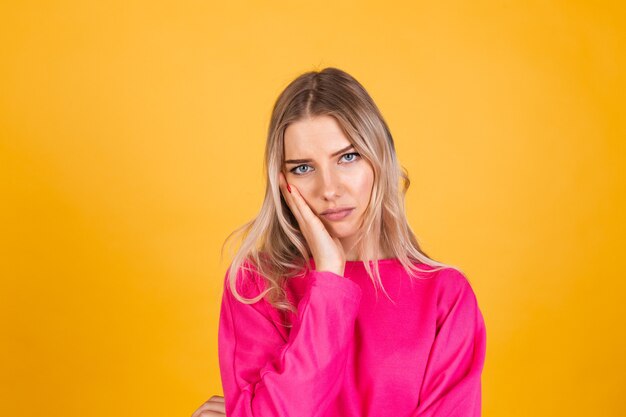 Jolie femme européenne en chemisier rose sur mur jaune