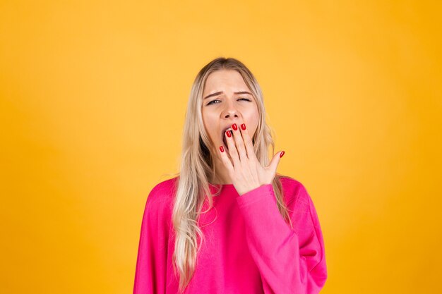 Jolie femme européenne en chemisier rose sur mur jaune