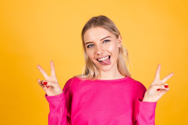 Jolie femme européenne en chemisier rose sur mur jaune