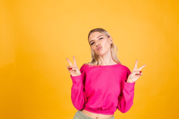 Jolie femme européenne en chemisier rose sur mur jaune