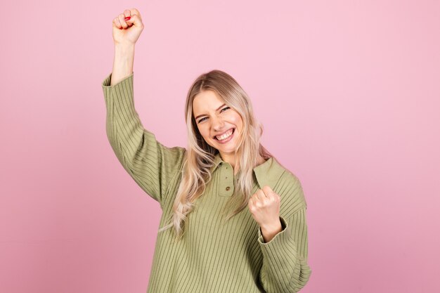 Jolie femme européenne en pull tricoté décontracté sur mur rose
