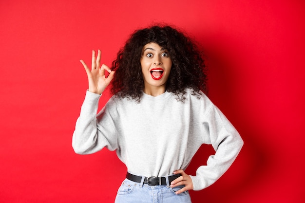 Une jolie femme excitée dit oui en montrant un geste correct et en ayant l'air enthousiaste d'accord ou comme quelque chose m...