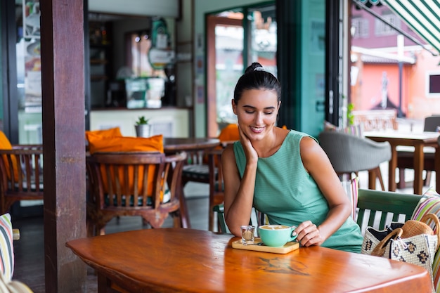 Jolie Femme Heureuse Calme élégante En Robe D'été Verte Est Assise Avec Un Café Au Café En Profitant Du Matin