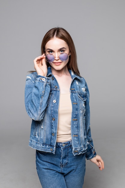 Jolie femme heureuse souriante faisant selfie photo isolé sur blanc studio mur habillé jeans et chemise en jean portant des lunettes de soleil jaune tenue de style hipster