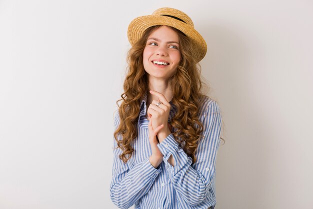 Jolie femme innocente avec une coiffure frisée portant un chapeau de paille