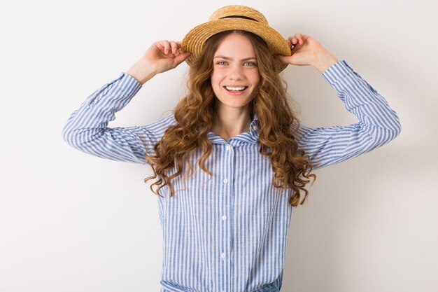 Jolie femme innocente avec une coiffure frisée portant un chapeau de paille