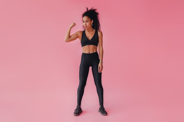 Photo gratuite jolie femme en leggings noirs et tenue de fitness supérieure sur mur isolé rose