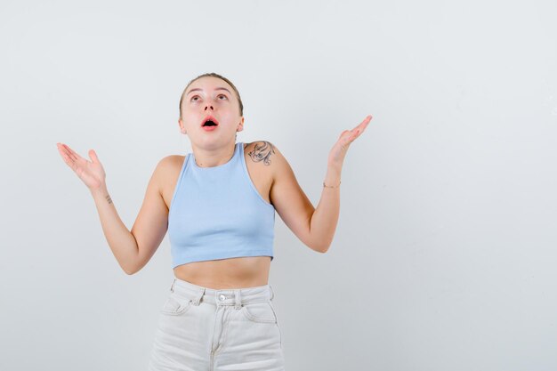 Jolie femme montre qu'elle ne sait rien sur fond blanc