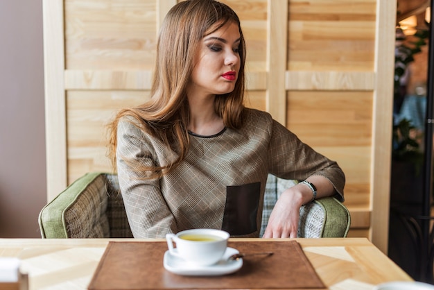 Jolie femme penser tout en ayant le thé