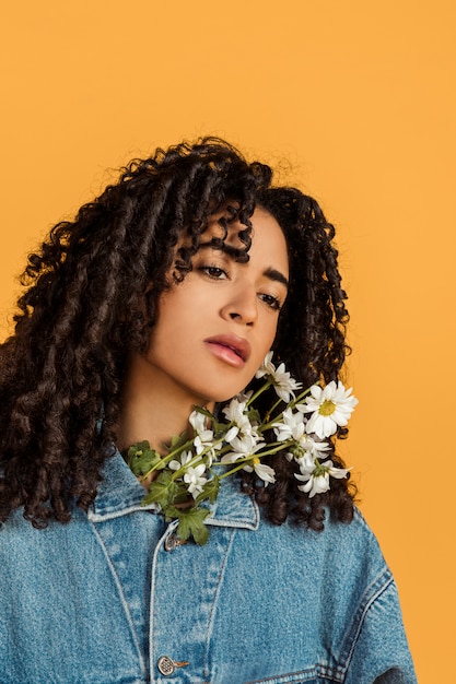 Jolie femme pensive ethnique avec des fleurs