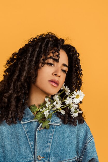 Jolie femme pensive ethnique avec des fleurs