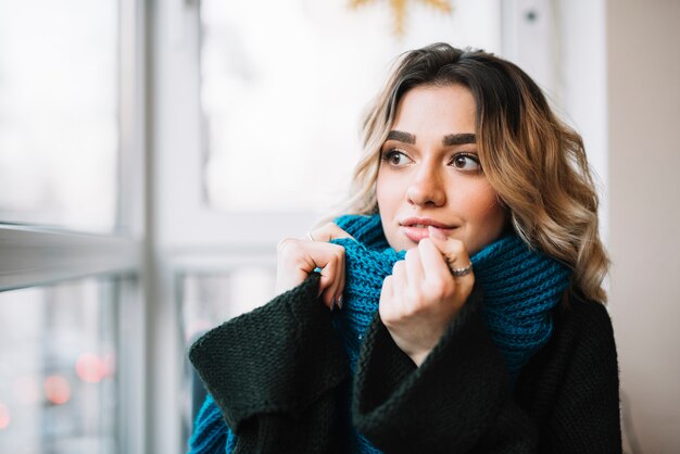 Jolie femme pensive près de la fenêtre