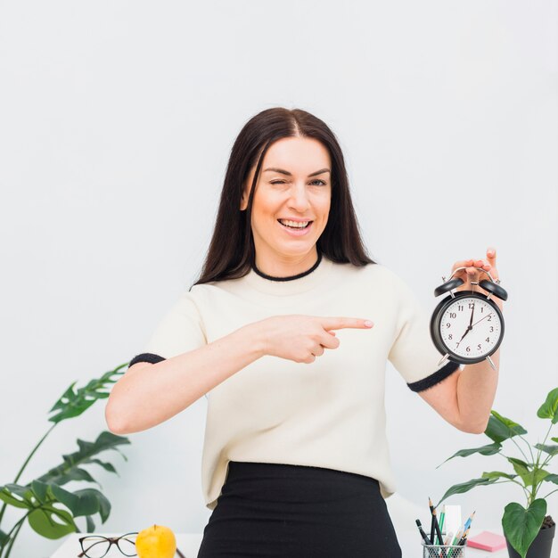 Jolie femme pointant son doigt sur l&#39;horloge