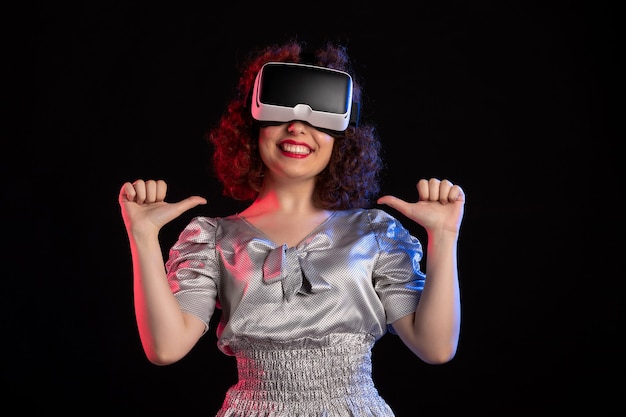 Jolie femme portant un casque de réalité virtuelle sur une surface sombre