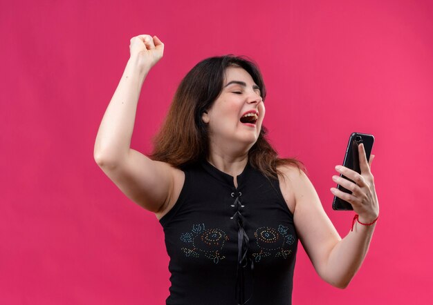 Jolie femme portant un chemisier noir a l'air de se réjouir au téléphone