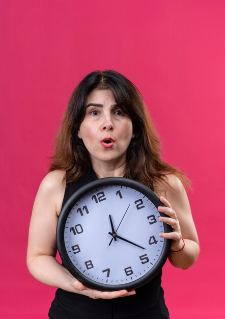 Jolie femme portant un chemisier noir peur d'être en retard derrière l'horloge