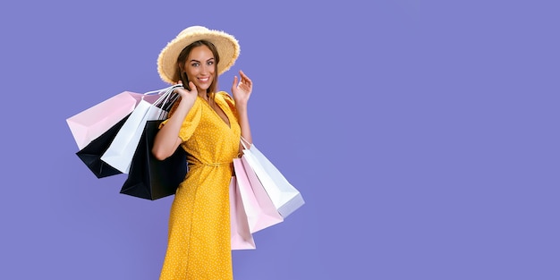 Jolie femme porte de nouveaux vêtements tout en tenant des emballages colorés sur fond de couleur grandes ventes