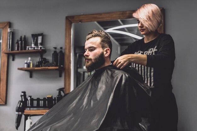 Jolie femme prépare le client dans le salon de coiffure