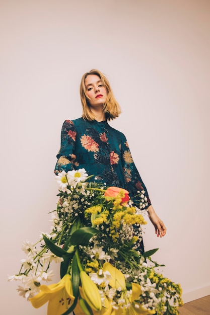 Jolie femme en robe montrant le bouquet de fleurs fraîches