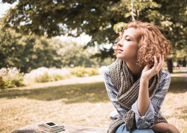 Jolie femme rousse assise sur un banc dans le parc