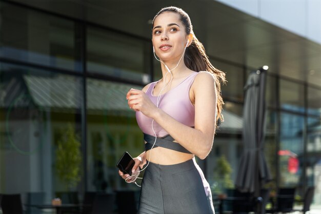 Jolie femme s'exécute dans la ville avec un téléphone portable à la main