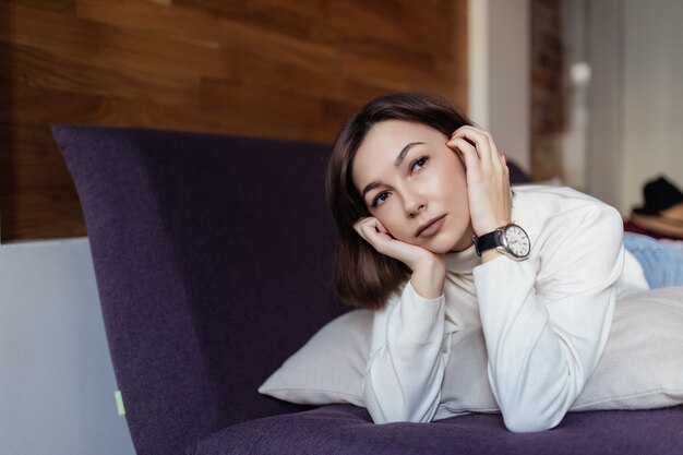 Jolie femme se détend sur le lit à la maison après le travail