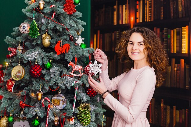 Jolie femme se prépare à l&#39;arbre de Noël debout dans la chambre
