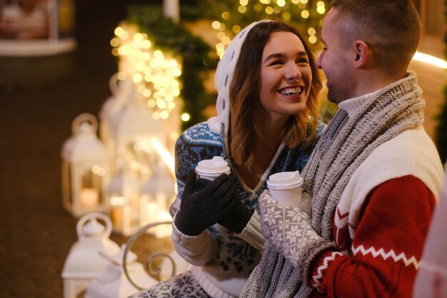 Une jolie femme se sent heureuse avec son homme qui savoure une boisson chaude le soir de Noël.