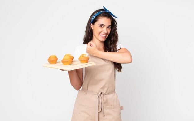 Jolie femme se sentant heureuse et faisant face à un défi ou célébrant et tenant un plateau de muffins