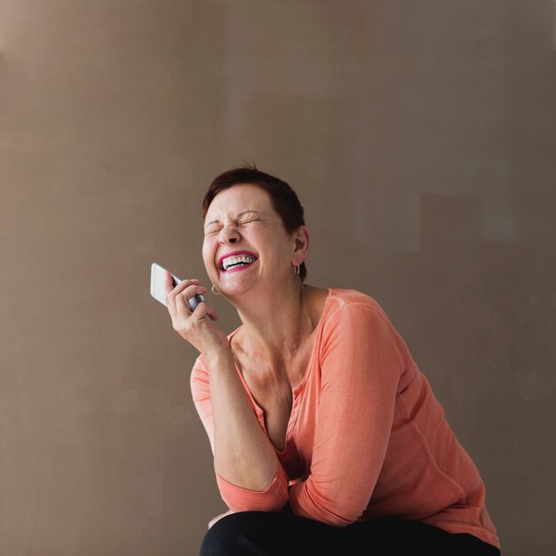 Jolie femme senior avec téléphone en riant