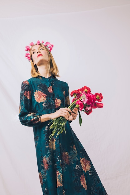 Jolie femme sensuelle avec guirlande sur la tête et bouquet de fleurs