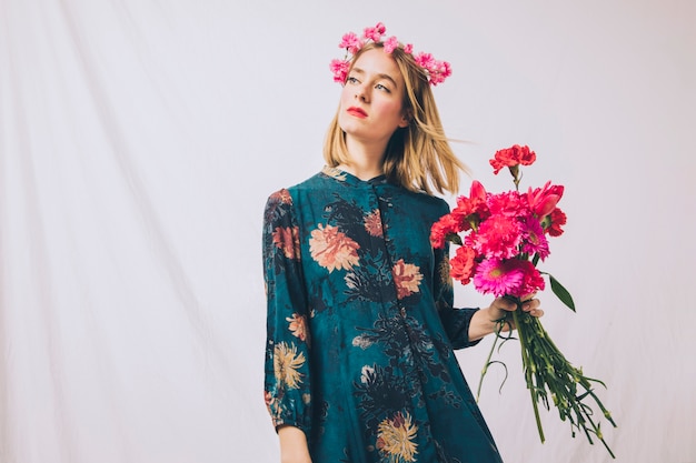 Jolie femme sensuelle avec guirlande sur la tête et bouquet de fleurs