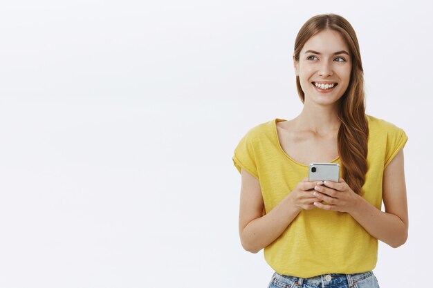 Jolie femme souriante à l'aide de téléphone mobile, SMS sur application ou réseau social