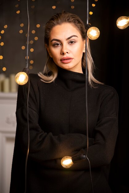 Jolie femme souriante vêtue d'un pull noir et posant