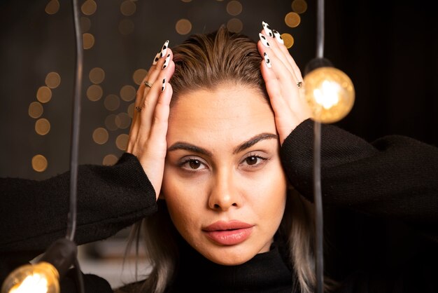 Jolie femme souriante vêtue d'un pull noir et posant